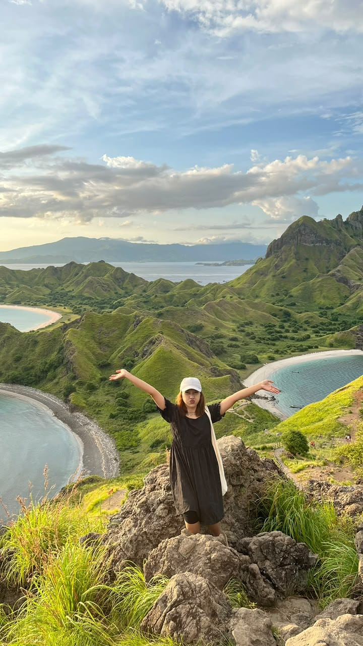 Pemandangan dari atas bukit Pulau Padar yang memperlihatkan perbukitan hijau dan tiga teluk dengan warna pantai yang berbeda di Taman Nasional Komodo.